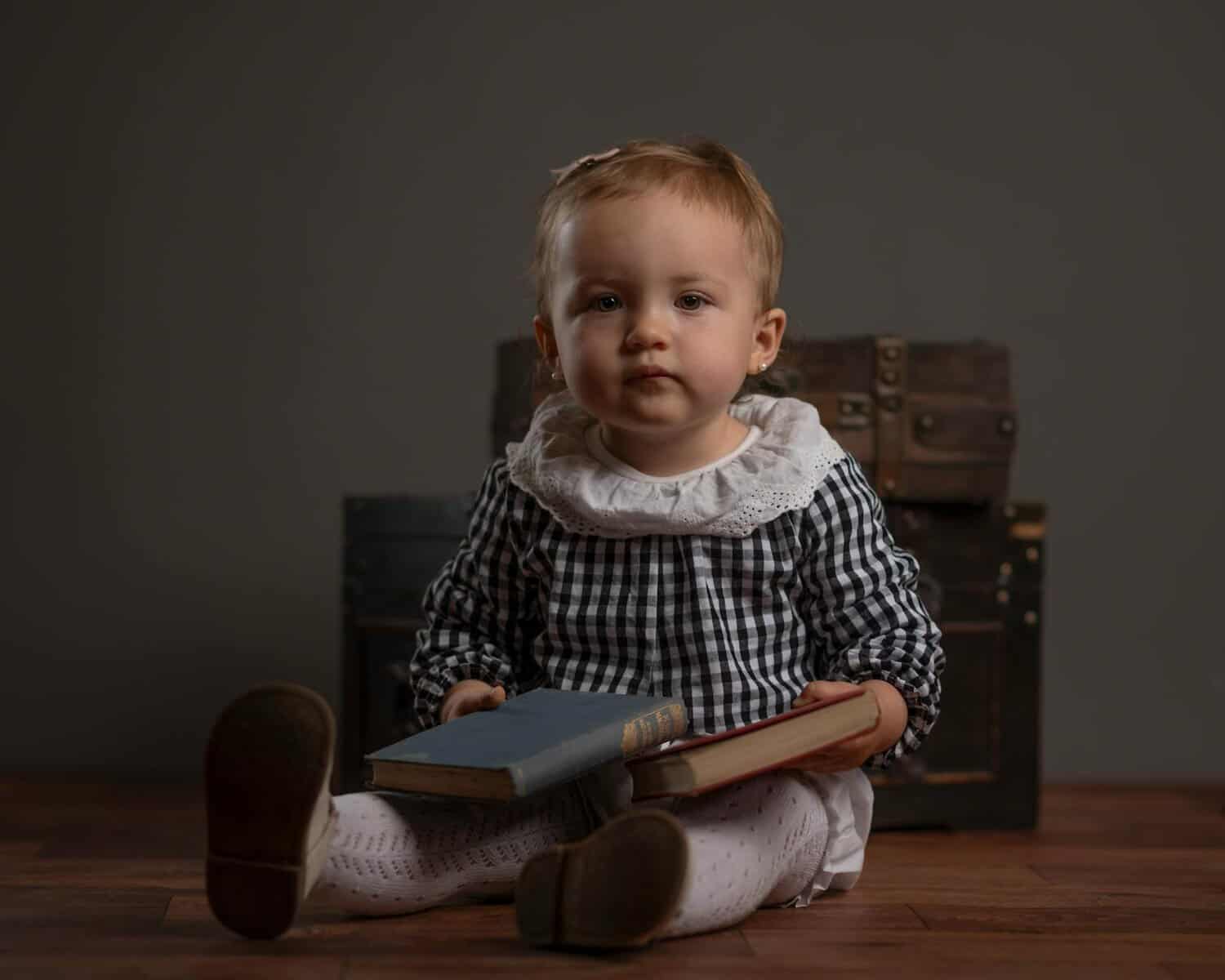 adorable baby sitting indoors with books